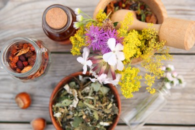 Photo of Tincture in bottle, different ingredients, mortar and pestle on wooden table, flat lay