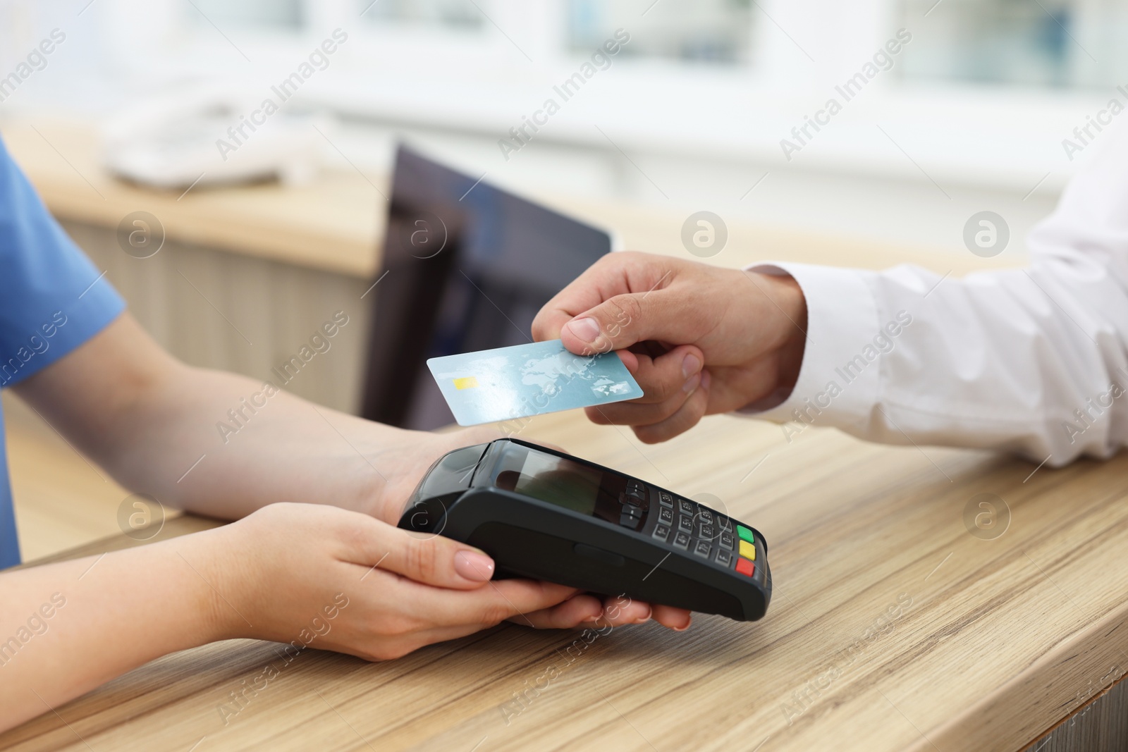 Photo of Receptionist taking payment from client via terminal at hospital, closeup