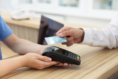 Receptionist taking payment from client via terminal at hospital, closeup