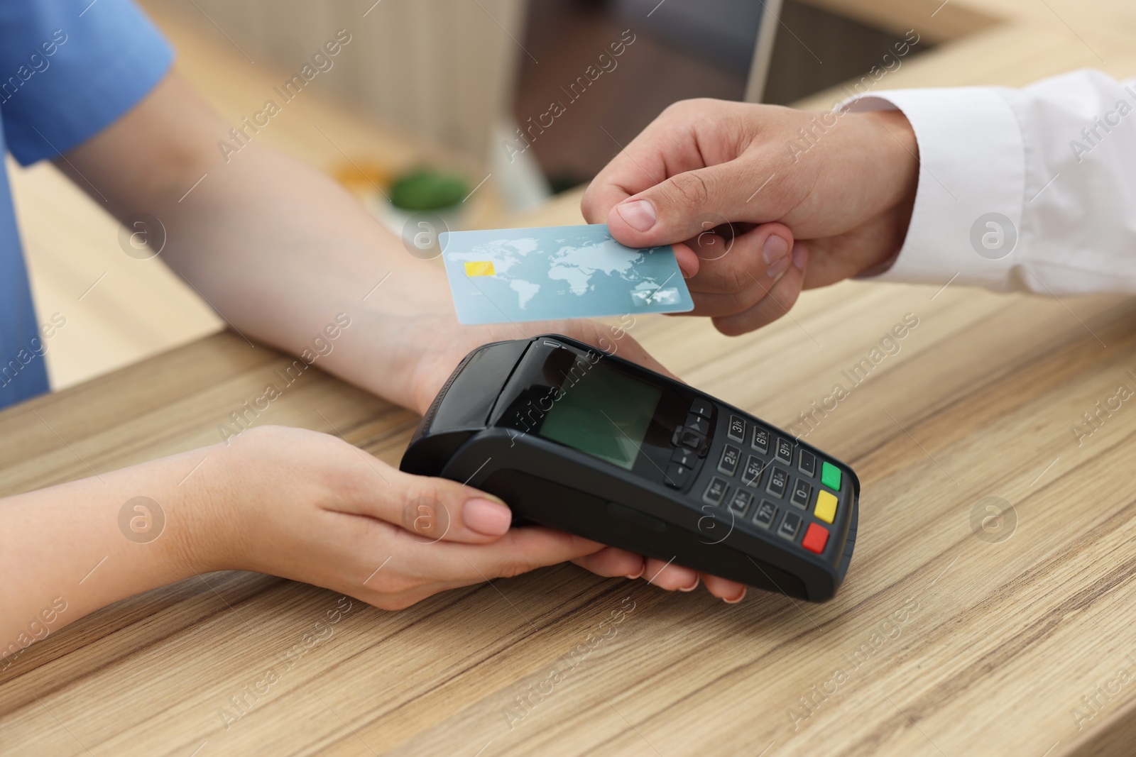 Photo of Receptionist taking payment from client via terminal at hospital, closeup