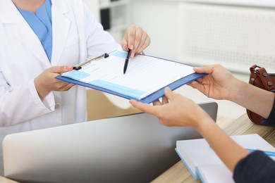 Photo of Professional receptionist working with patient at wooden desk in hospital, closeup