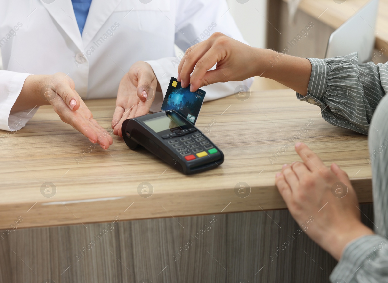 Photo of Receptionist taking payment from client via terminal at hospital, closeup