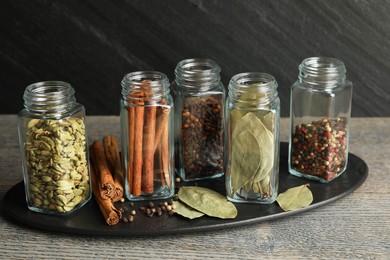 Photo of Different spices in glass jars on grey wooden table, closeup