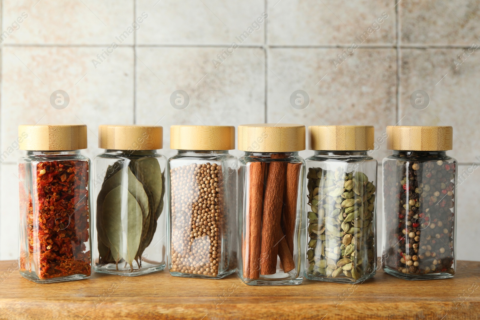 Photo of Different spices in glass jars on wooden table, closeup