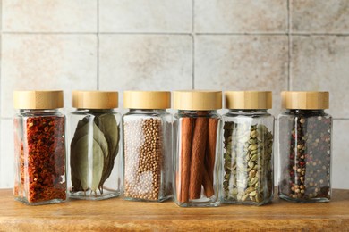 Photo of Different spices in glass jars on wooden table, closeup