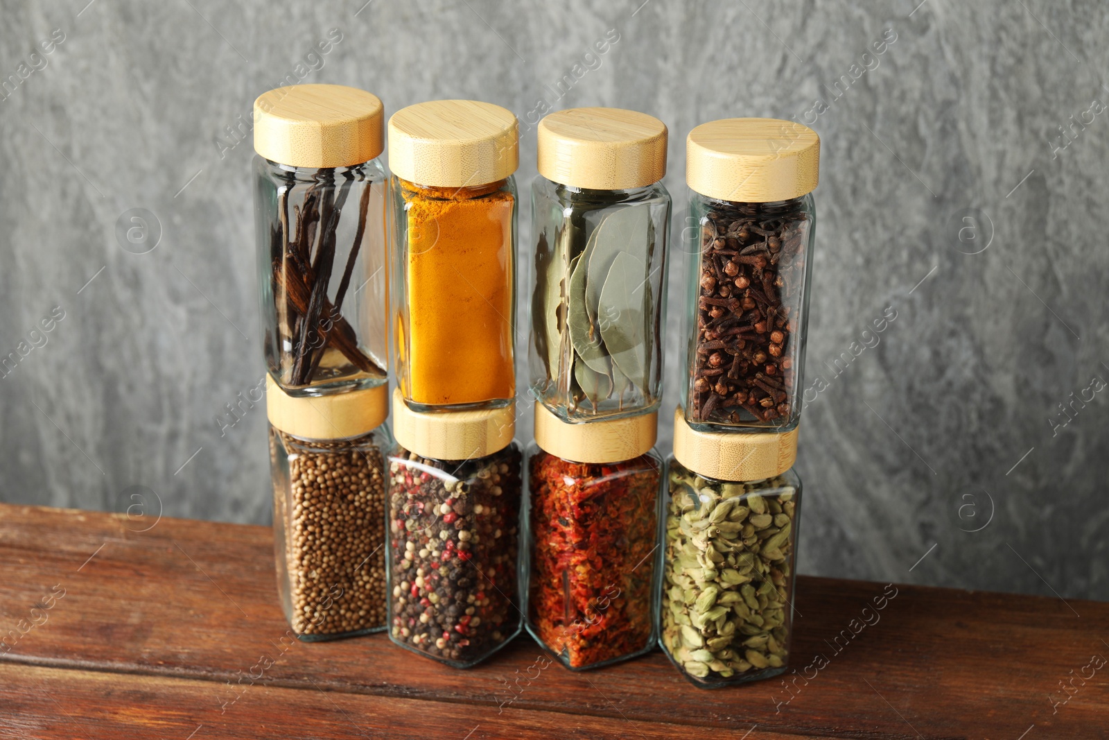 Photo of Different spices in glass jars on wooden table