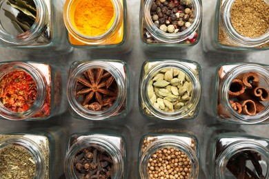 Photo of Different spices in glass jars on grey table, flat lay