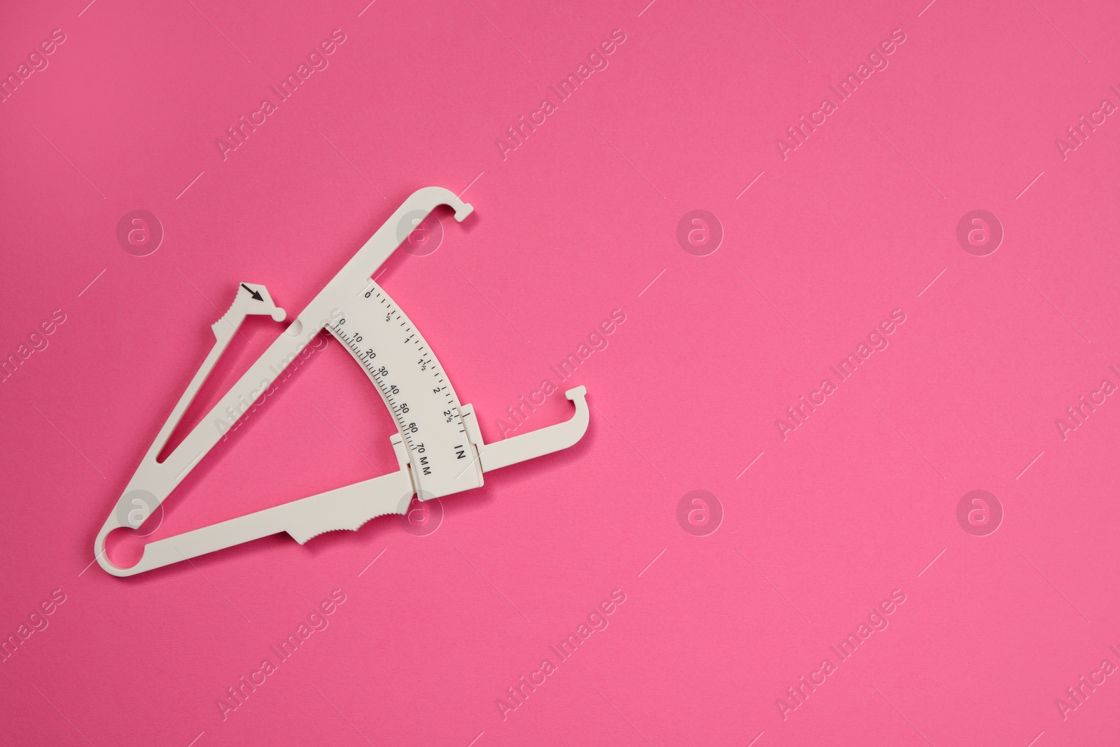 Photo of Plastic body fat caliper on pink background, top view. Space for text