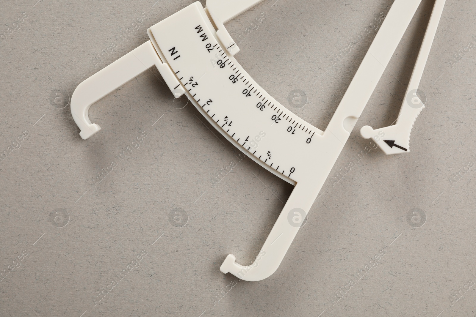 Photo of Plastic body fat caliper on grey background, top view