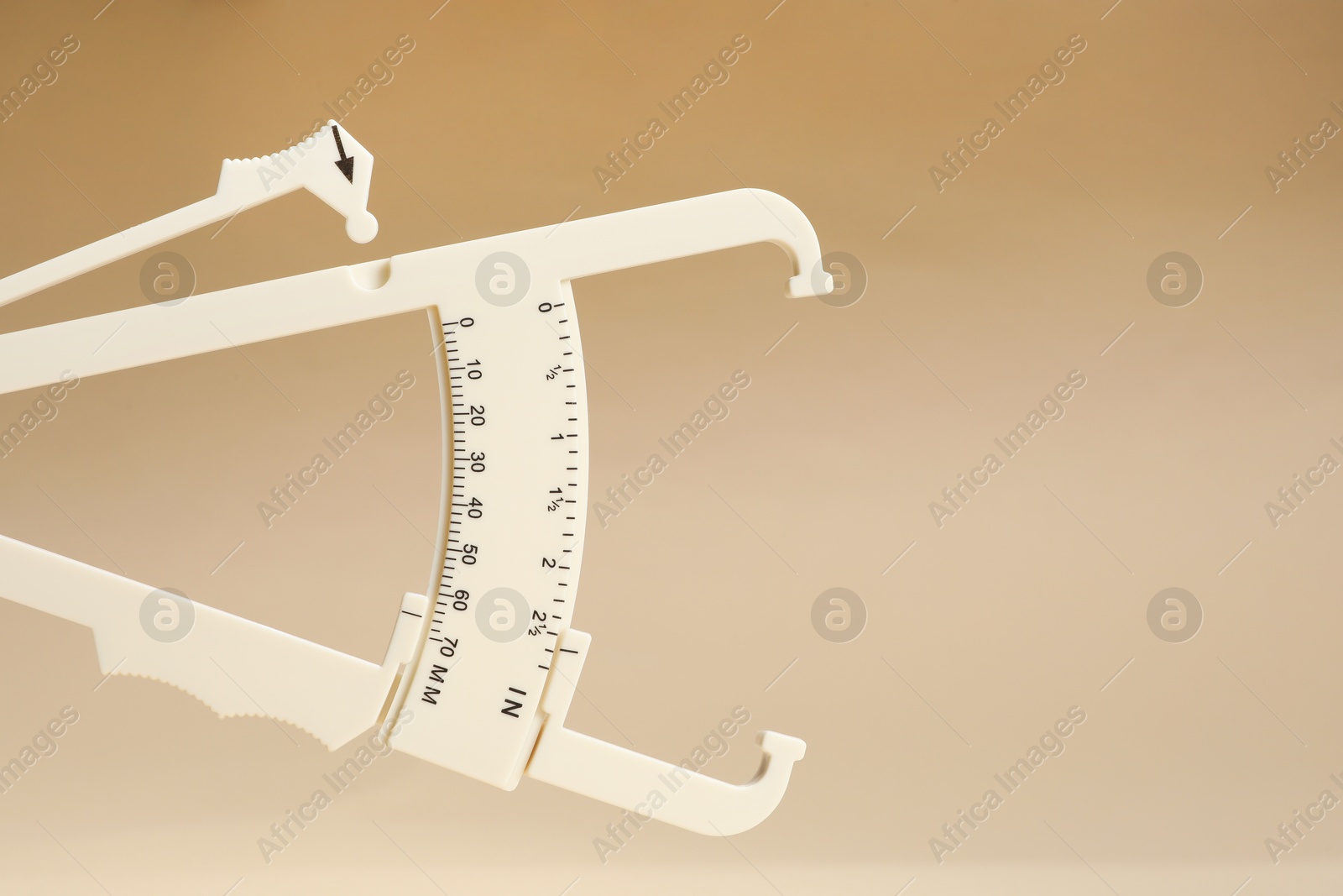 Photo of Plastic body fat caliper on beige background, closeup. Space for text