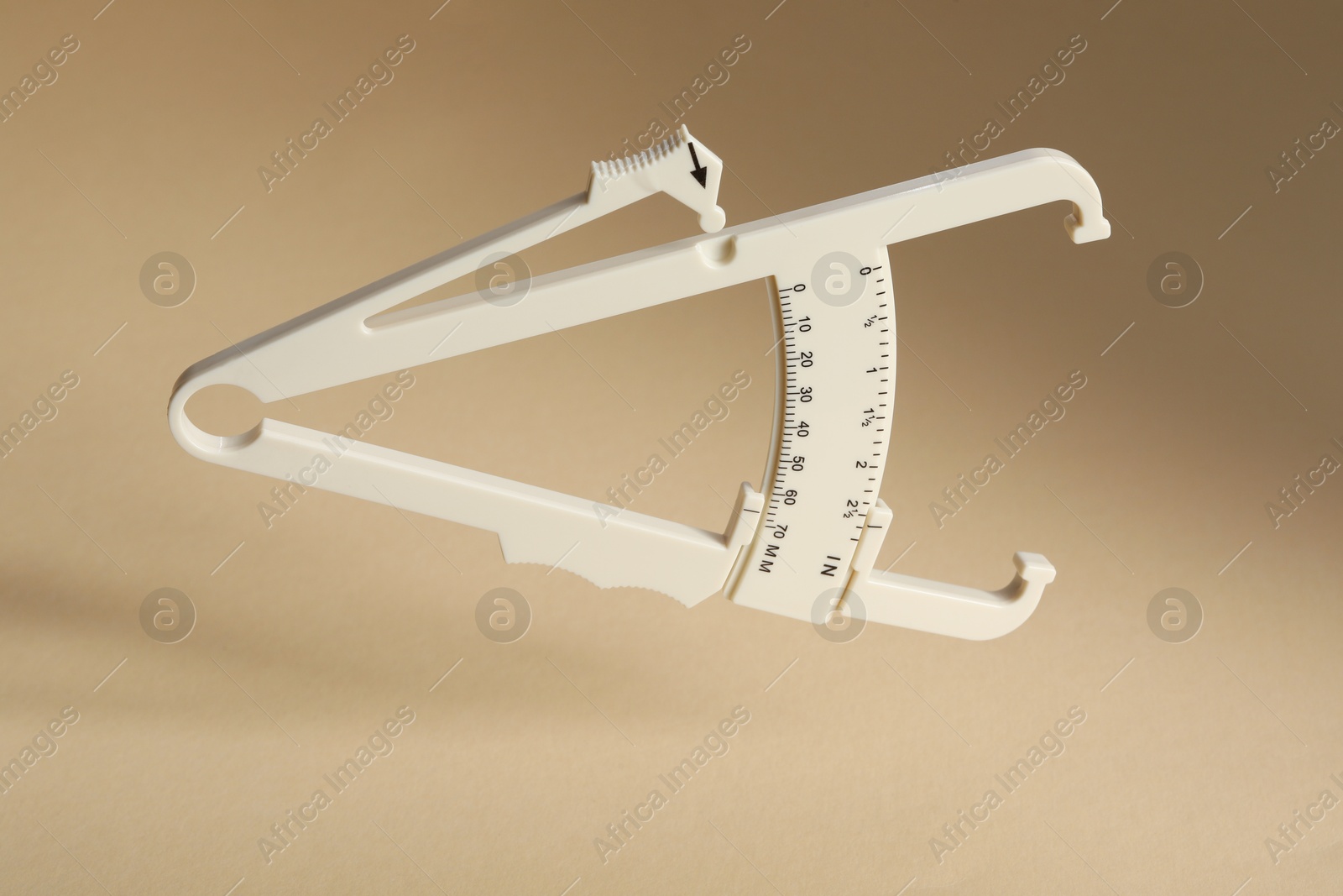 Photo of Plastic body fat caliper on beige background