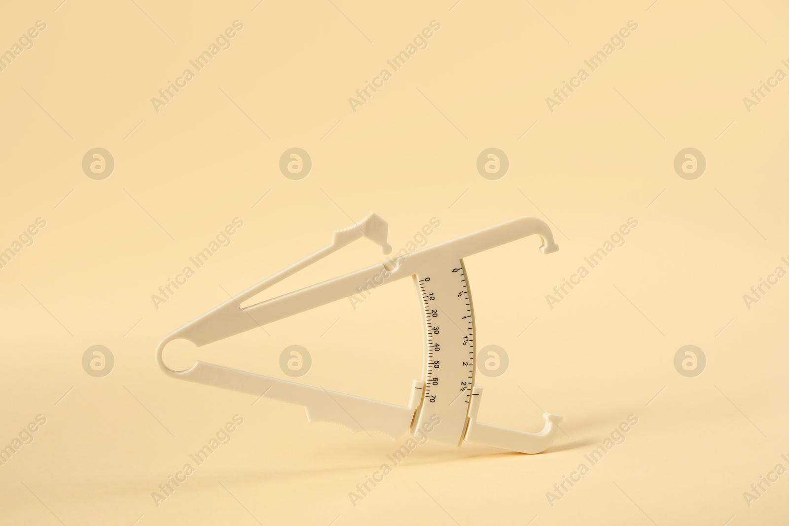 Photo of Plastic body fat caliper on beige background