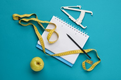 Photo of Flat lay composition with body fat caliper, measuring tape and notebook on light blue background