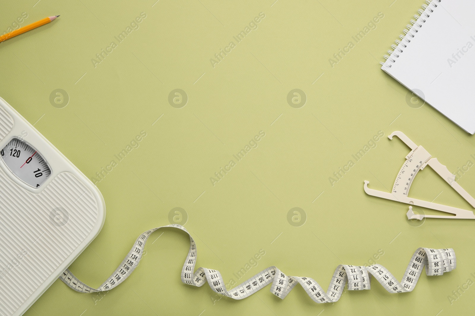 Photo of Body fat caliper, measuring tape, scale and notebook on light green background, flat lay. Space for text