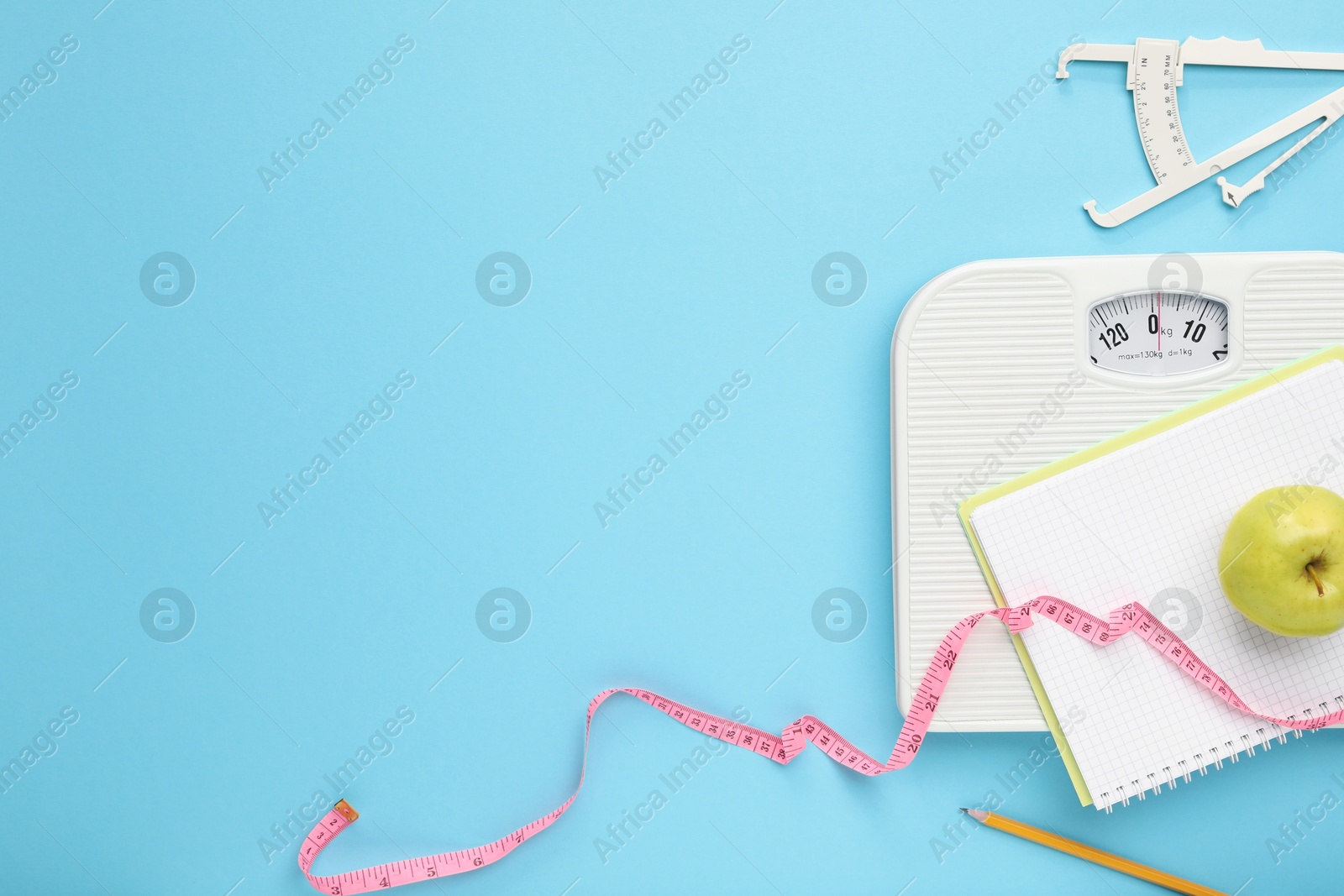 Photo of Flat lay composition with body fat caliper and scale on light blue background. Space for text