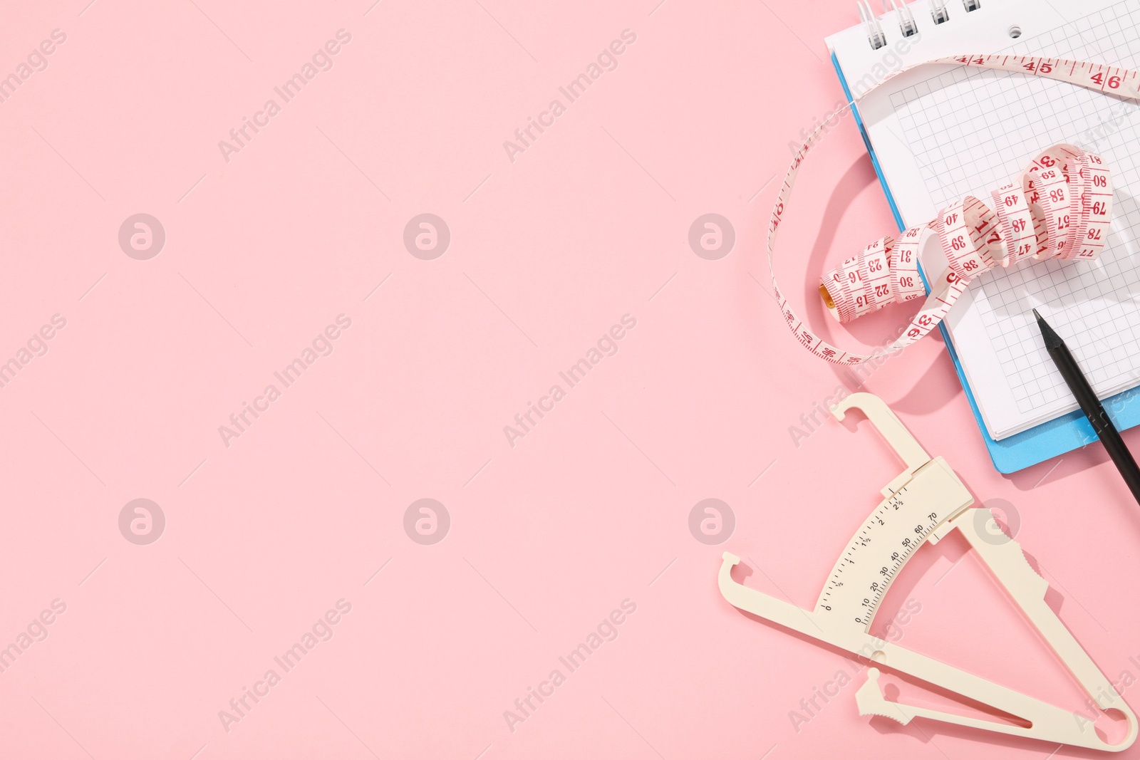 Photo of Body fat caliper, measuring tape, notebook and pencil on pink background, flat lay. Space for text