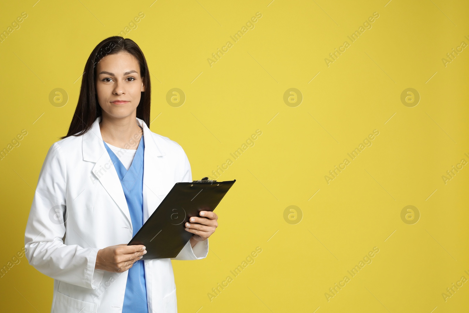 Photo of Portrait of beautiful nurse with clipboard on yellow background. Space for text