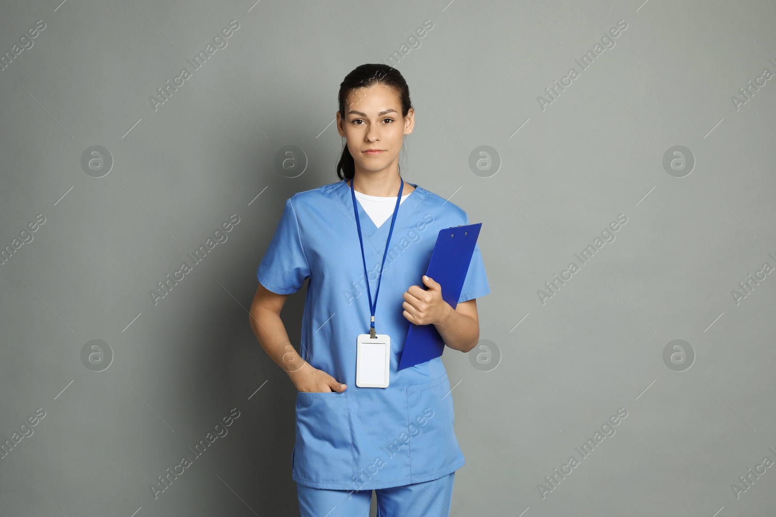 Photo of Portrait of beautiful nurse with clipboard on grey background