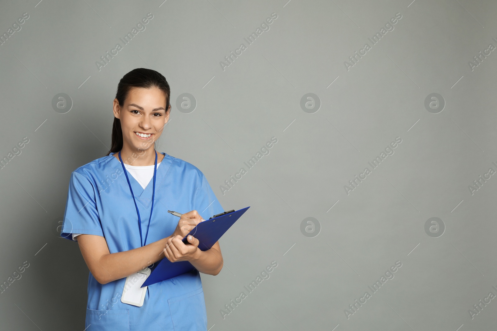 Photo of Portrait of smiling nurse with clipboard on grey background. Space for text