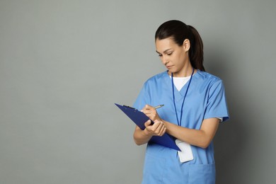 Photo of Portrait of beautiful nurse with clipboard on grey background. Space for text