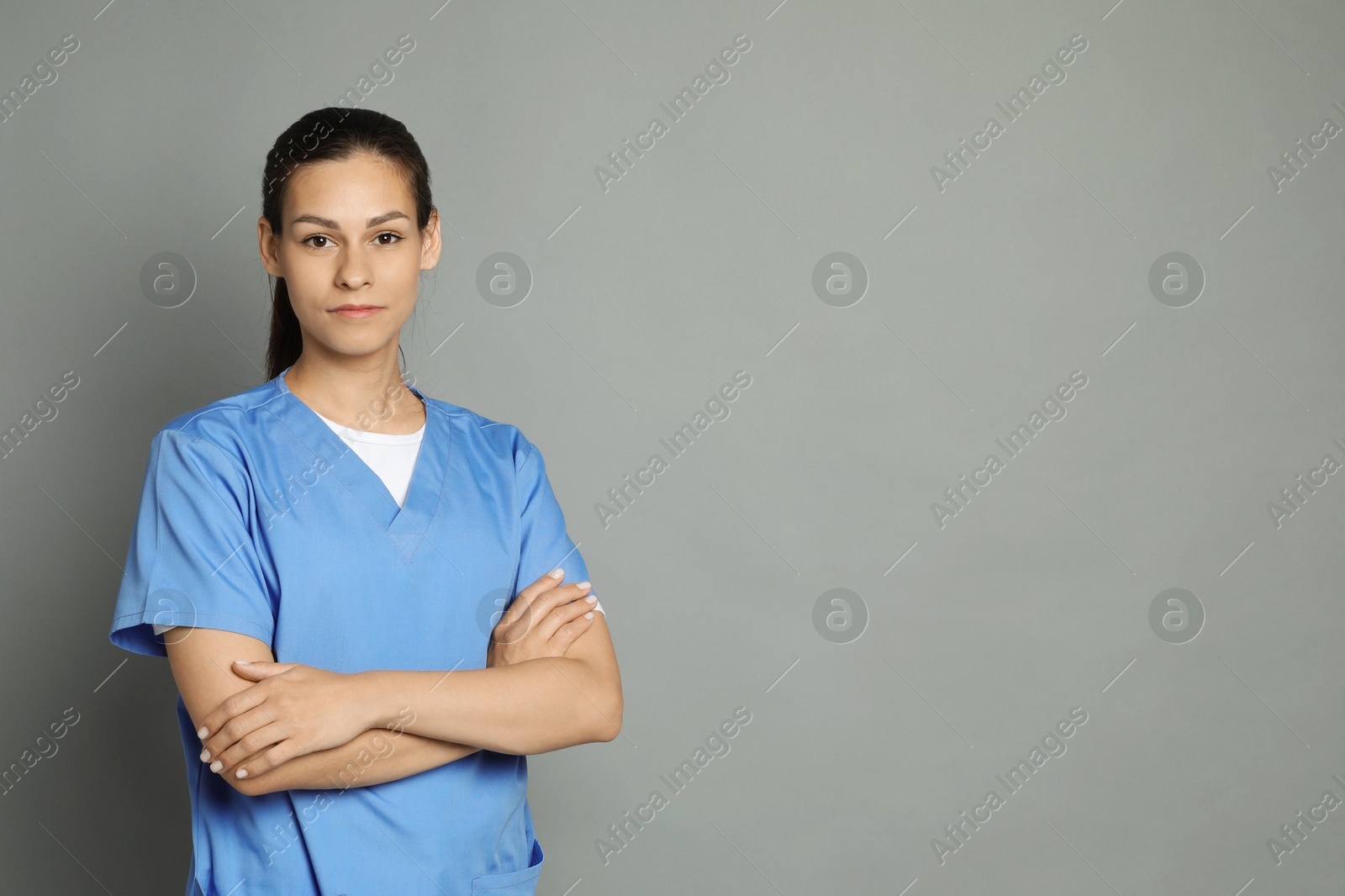 Photo of Portrait of beautiful nurse with crossed arms on grey background. Space for text