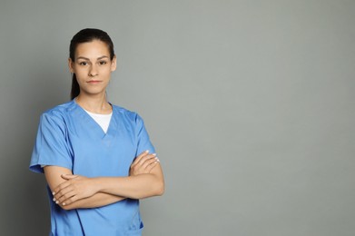 Portrait of beautiful nurse with crossed arms on grey background. Space for text