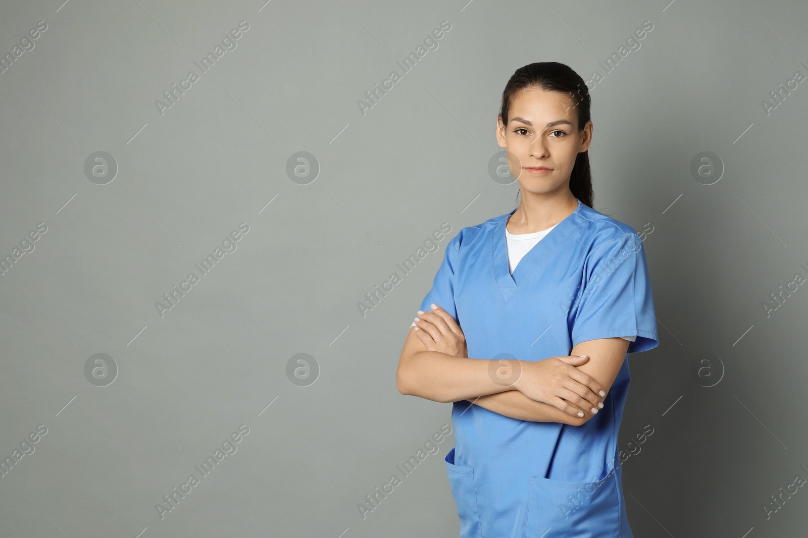 Photo of Portrait of beautiful nurse with crossed arms on grey background. Space for text