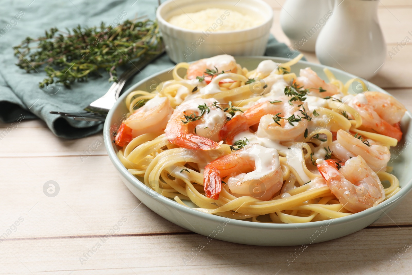 Photo of Delicious pasta with shrimps and creamy sauce on light wooden table, closeup