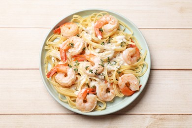 Photo of Delicious pasta with shrimps and creamy sauce on light wooden table, top view