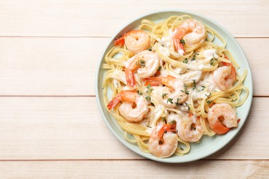 Photo of Delicious pasta with shrimps and creamy sauce on light wooden table, top view. Space for text