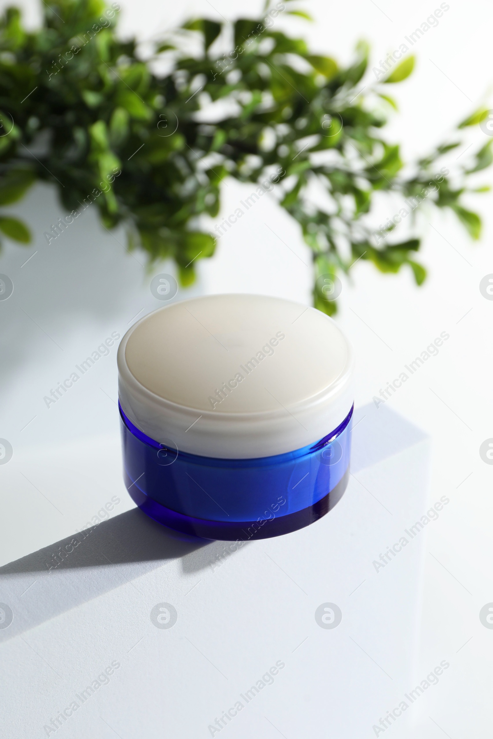 Photo of Facial cream in jar and floral decor on white background