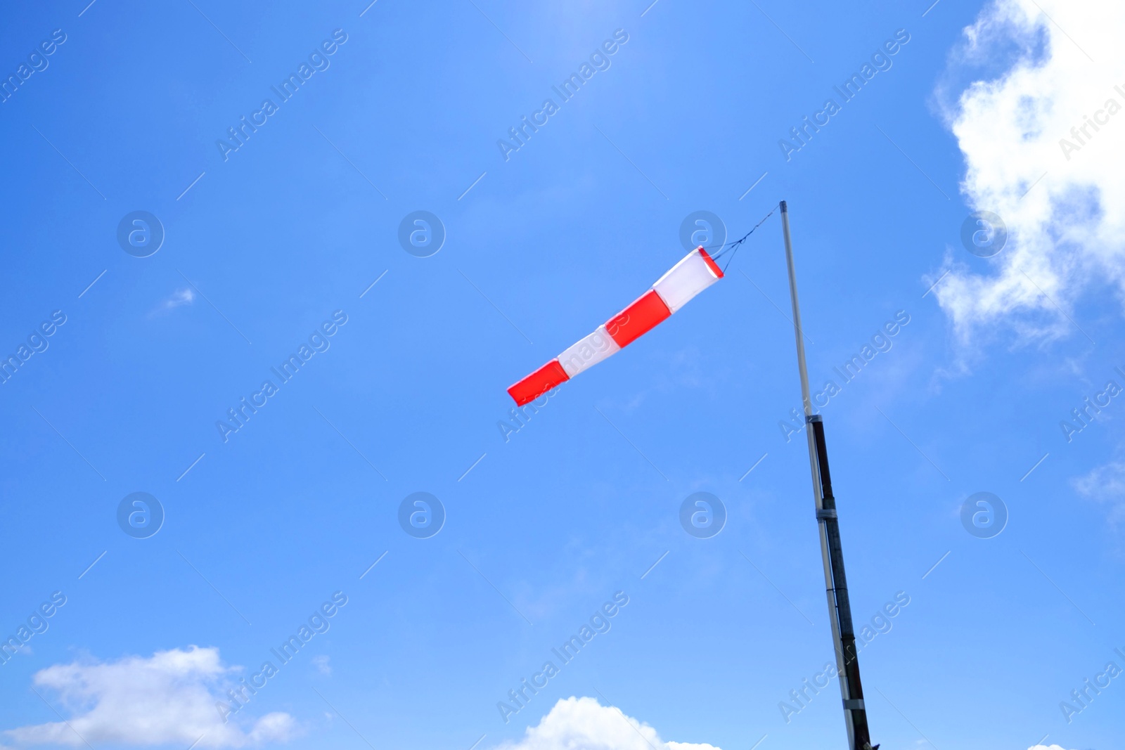 Photo of Striped windsock on pole against blue sky, space for text