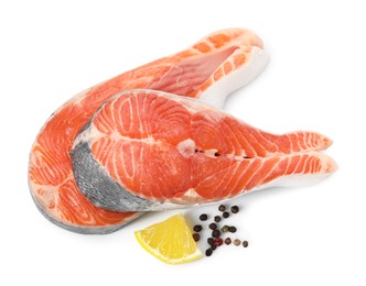 Photo of Two fresh salmon steaks, lemon and peppercorns isolated on white, above view