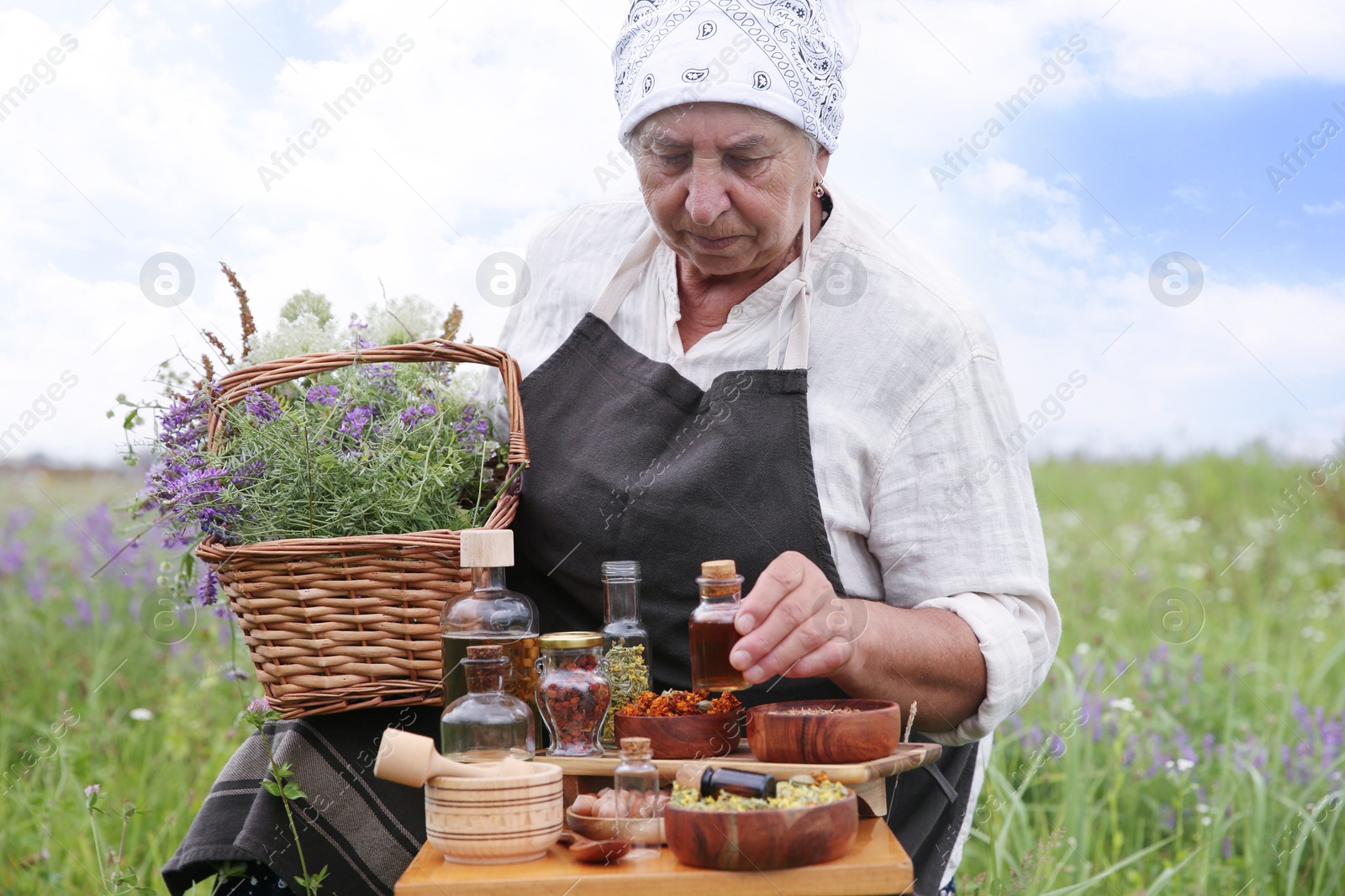 Photo of Senior woman with tincture and different ingredients outdoors