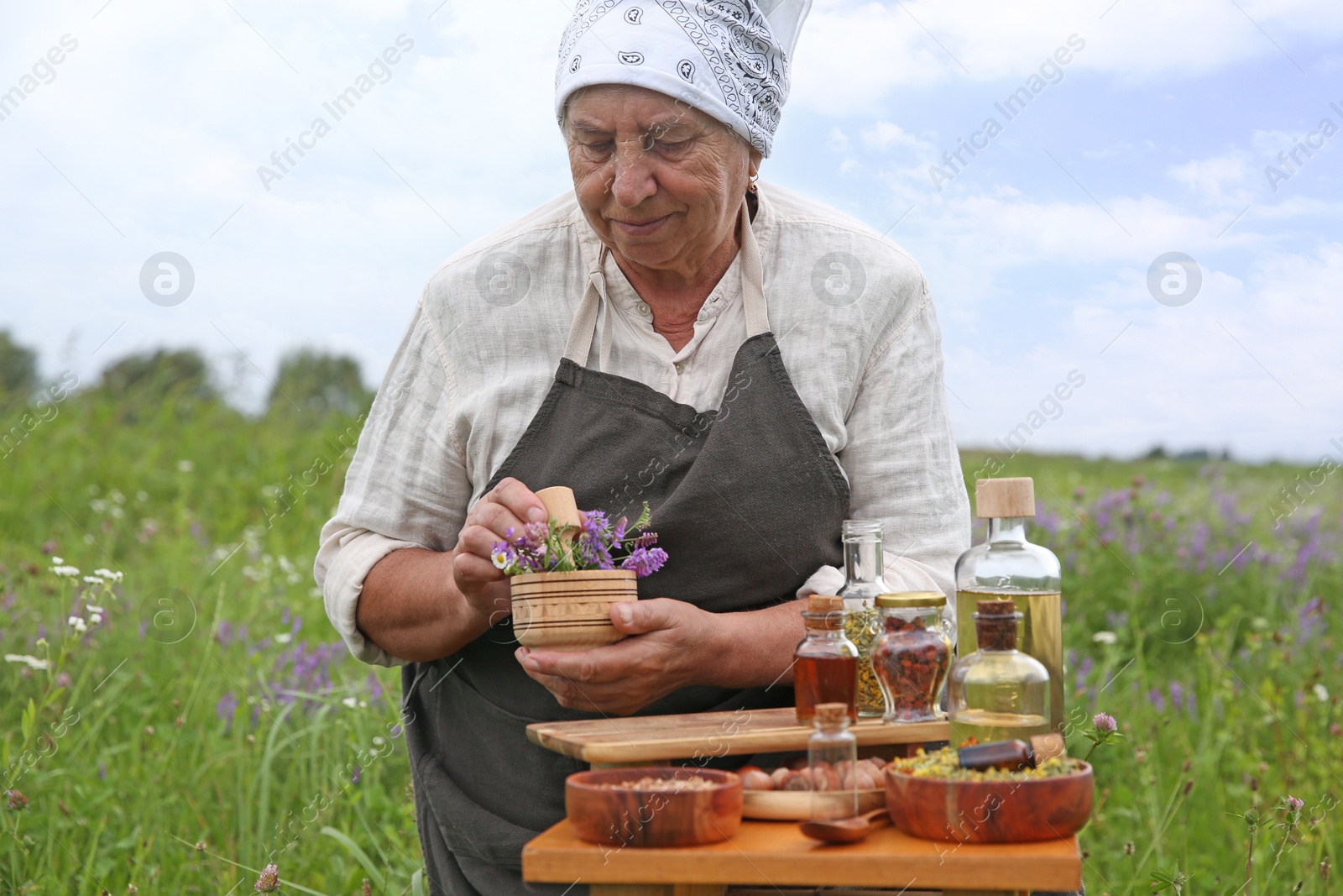 Photo of Senior woman with mortar and pestle making tincture outdoors