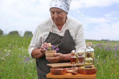 Senior woman with mortar and pestle making tincture outdoors