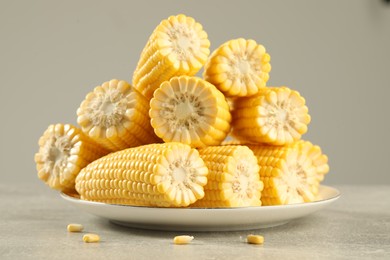 Photo of Halves of fresh ripe corncobs on grey table, closeup