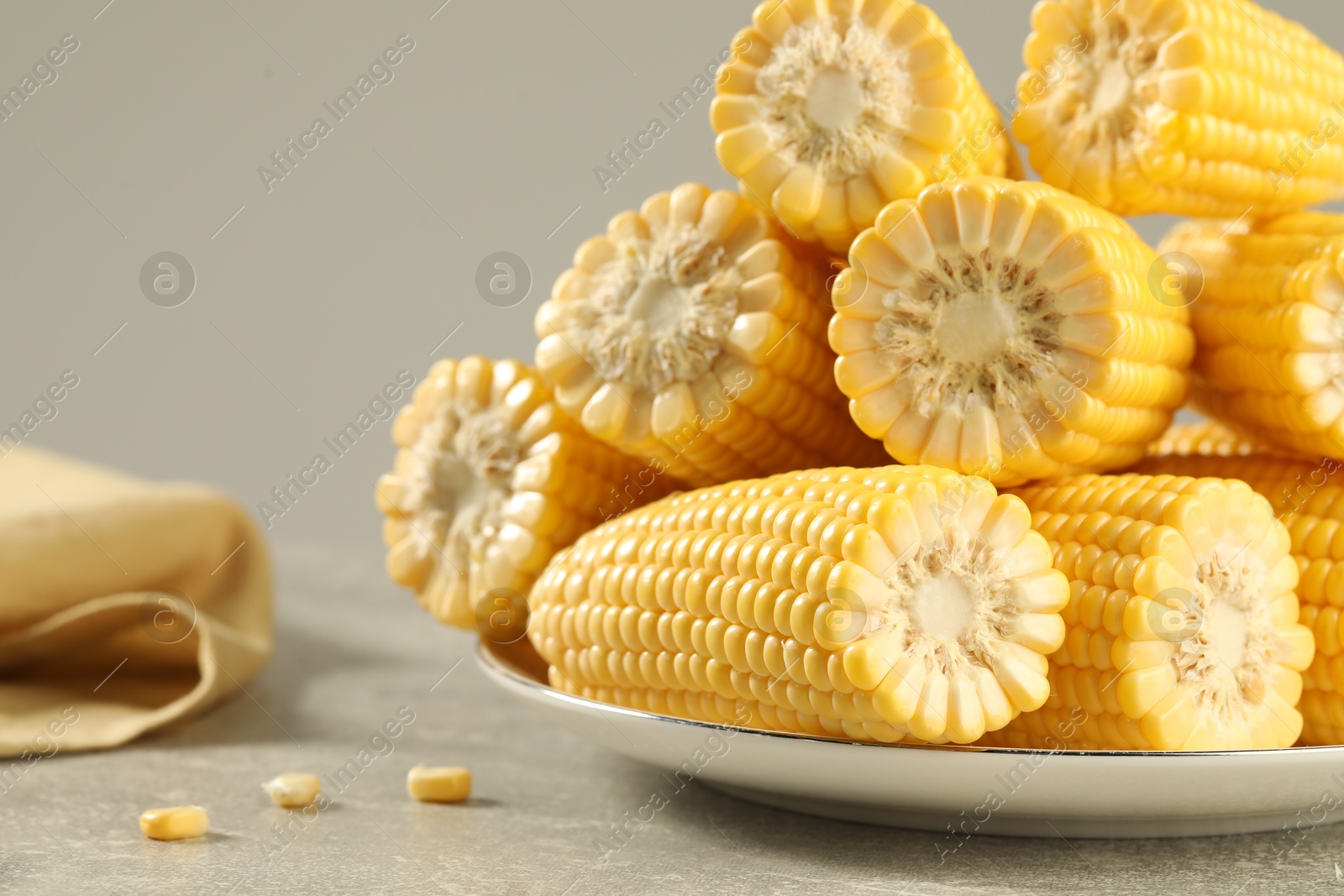 Photo of Halves of fresh ripe corncobs on grey table, closeup