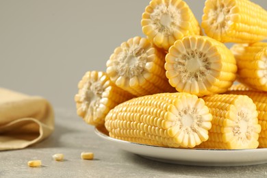 Photo of Halves of fresh ripe corncobs on grey table, closeup