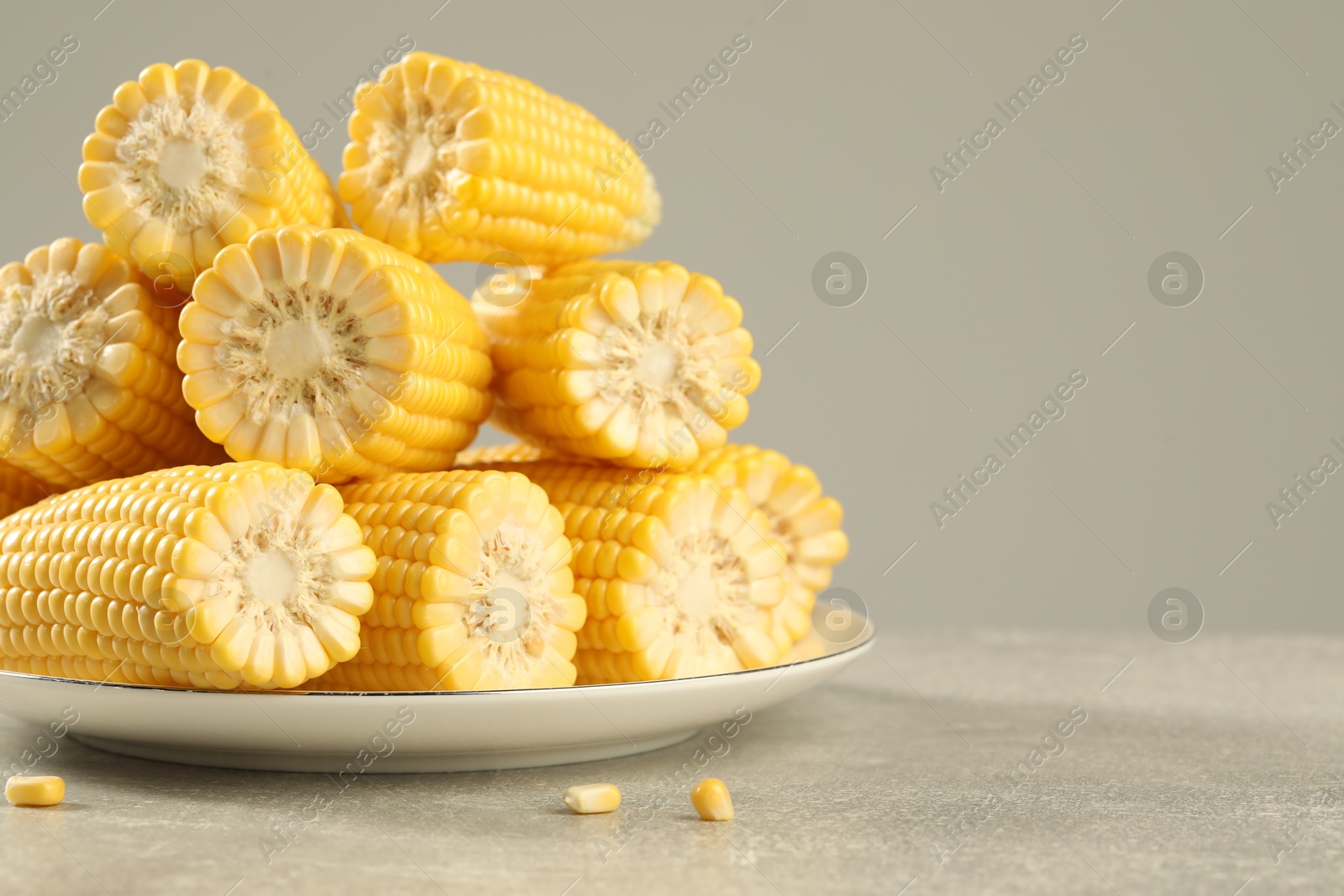 Photo of Halves of fresh ripe corncobs on grey table, closeup. Space for text