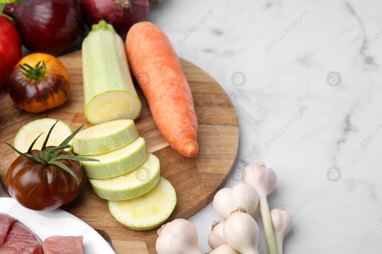 Photo of Different vegetables and raw meat for stew on white marble table, space for text