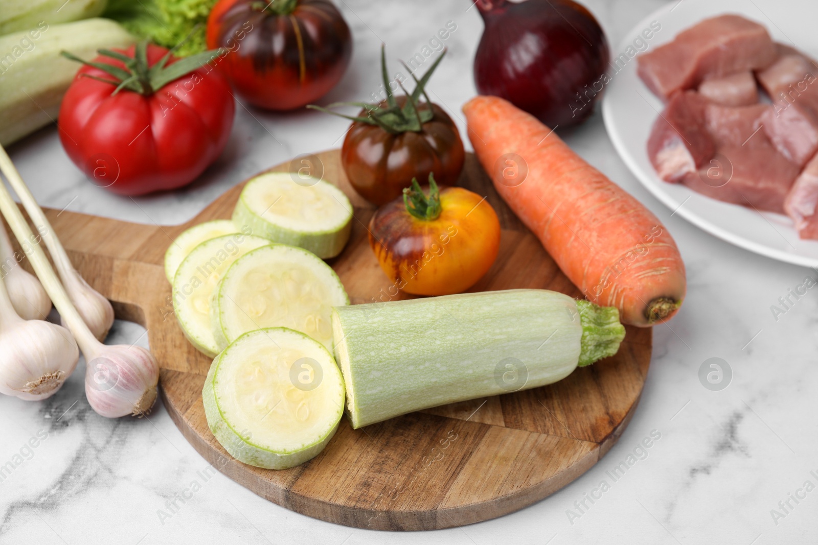 Photo of Different vegetables and raw meat for stew on white marble table