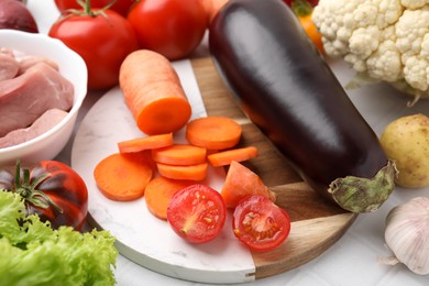 Different vegetables and raw meat for stew on white table