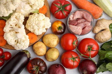 Different vegetables and raw meat for stew on light grey table, flat lay