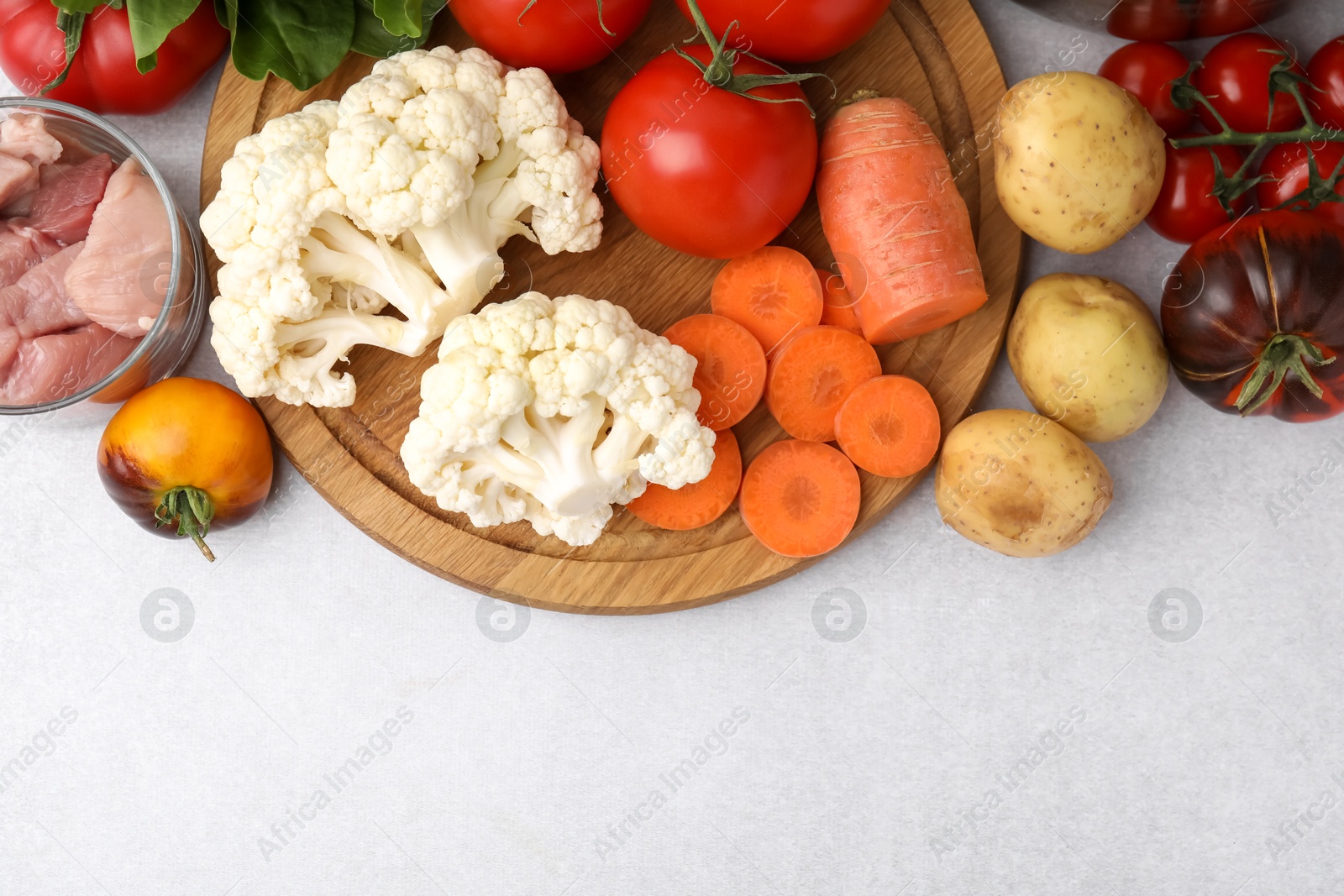 Photo of Different vegetables and raw meat for stew on light grey table, top view