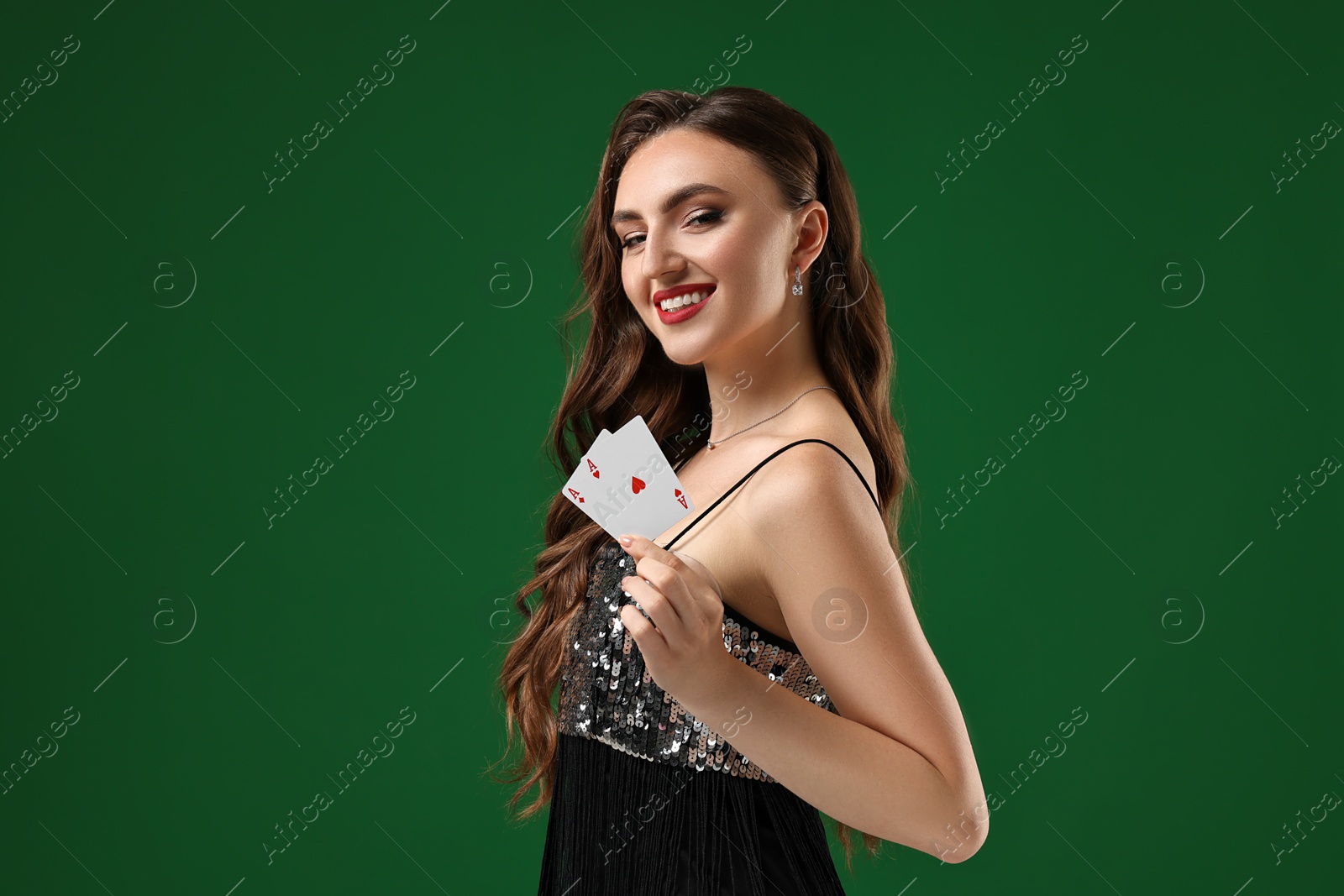 Photo of Poker game. Smiling woman with playing cards on green background