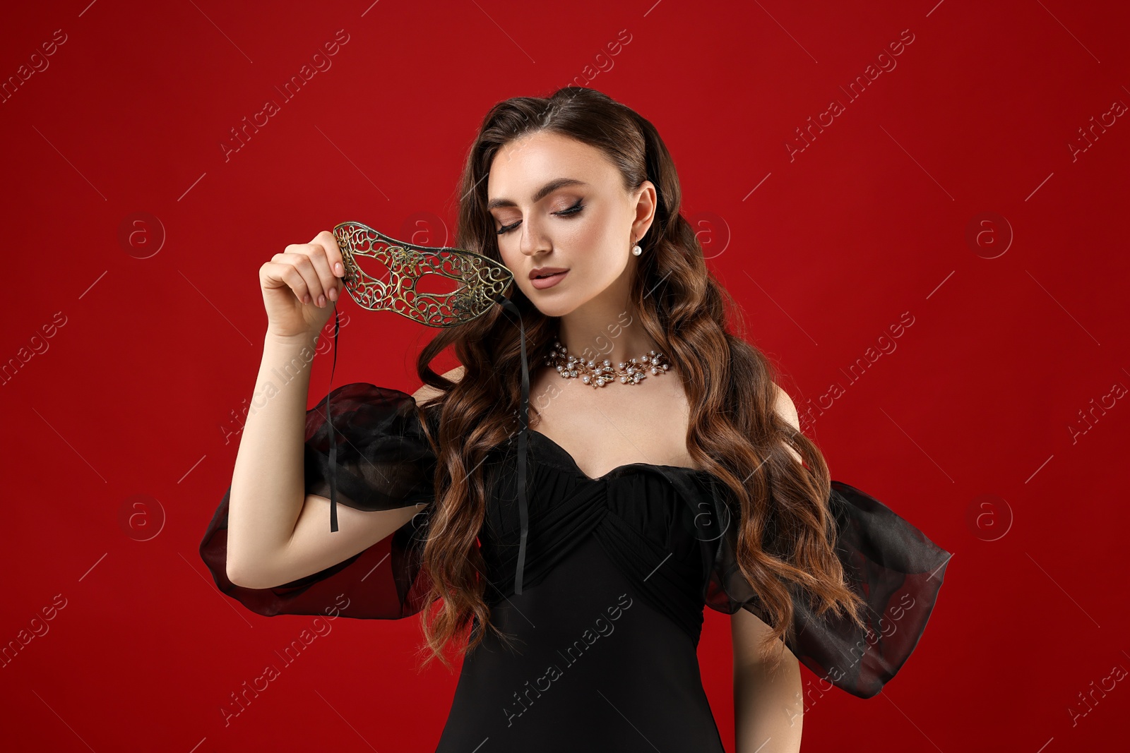 Photo of Beautiful woman with carnival mask on red background