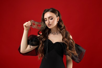 Photo of Beautiful woman with carnival mask on red background