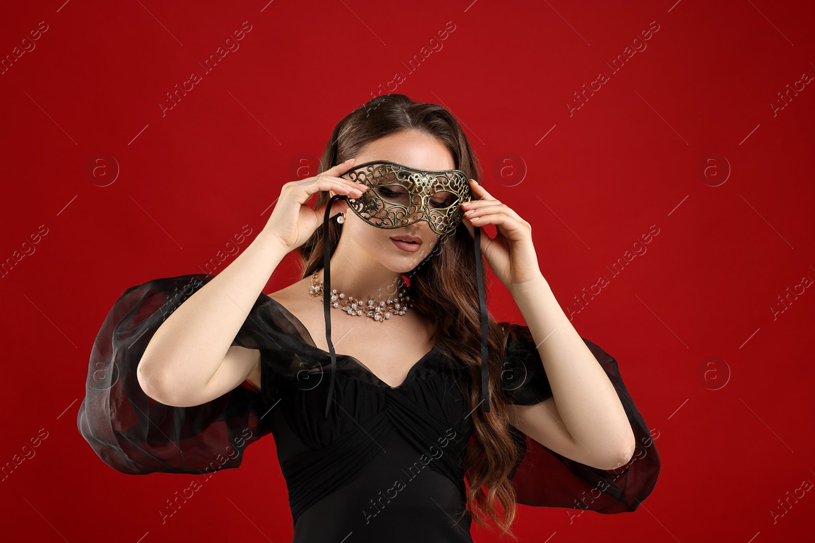 Photo of Beautiful woman wearing carnival mask on red background