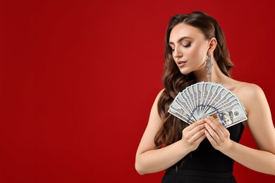 Charming woman with dollar banknotes on red background. Space for text